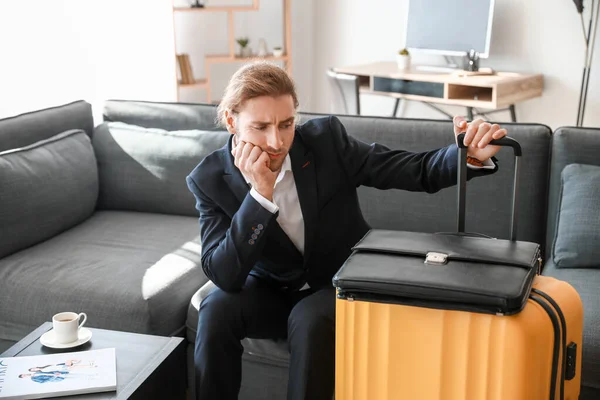 Young man with packed luggage for business trip at home — Stock Photo, Image