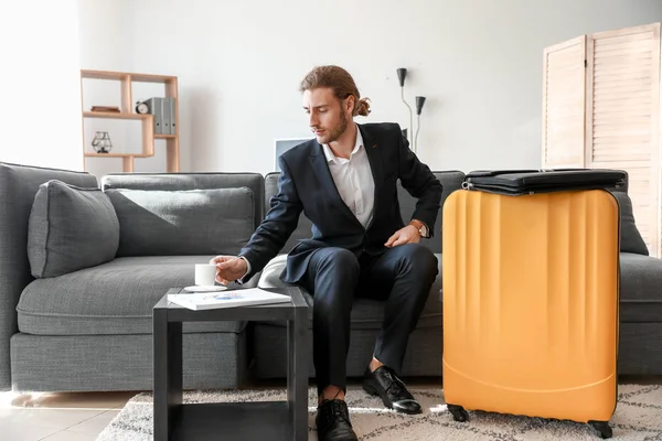Young man with packed luggage for business trip at home — Stock Photo, Image