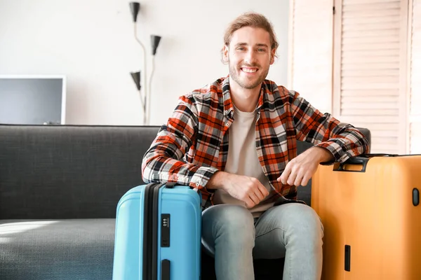 Young man with packed luggage at home — Stock Photo, Image
