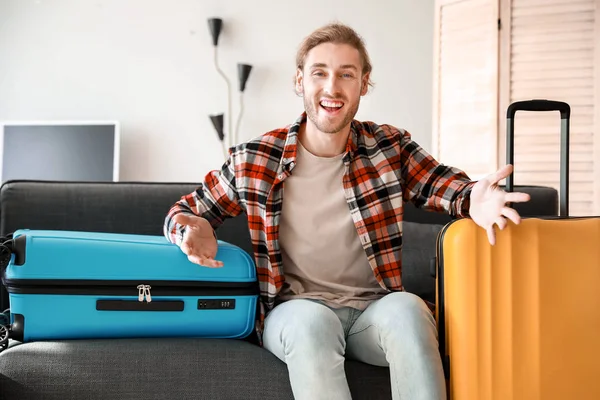 Young man with packed luggage at home — Stock Photo, Image