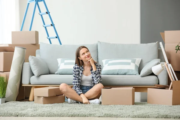 Happy young woman with moving boxes in new house — Stock Photo, Image