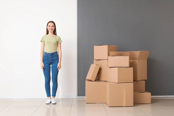 Happy young woman with moving boxes in new house — Stock Photo, Image