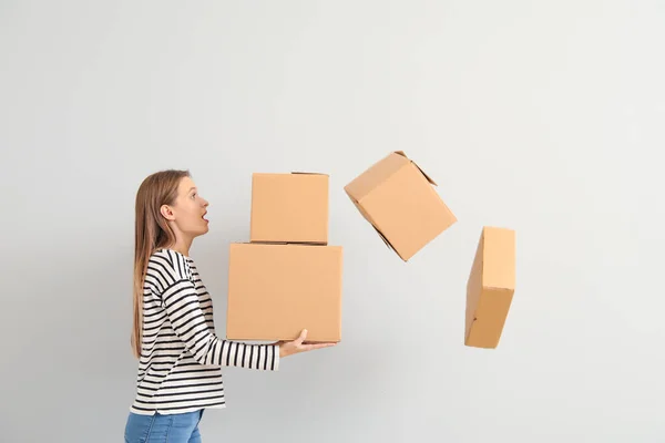 Mulher incomodada soltando caixas de papelão no fundo claro — Fotografia de Stock