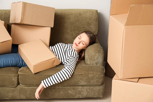 Alvó nő egy halom mozgó doboz feküdt a kanapén az új házban — Stock Fotó