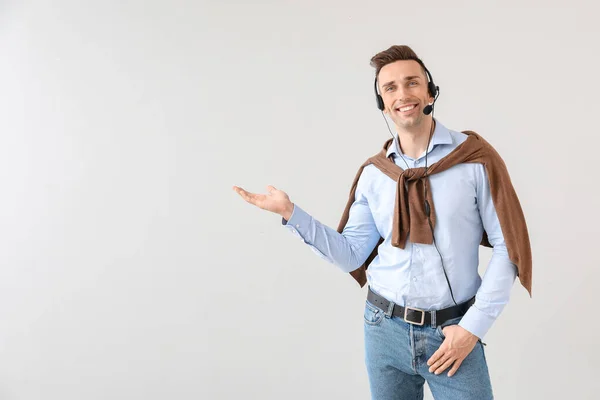 Male technical support agent showing something on light background — Stock Photo, Image