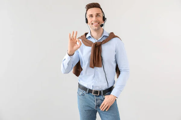 Male technical support agent showing OK gesture on light background — Stock Photo, Image