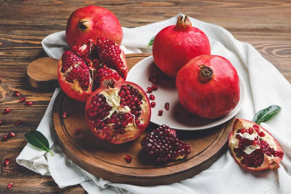 Board with tasty pomegranate on wooden table — Stock Photo, Image