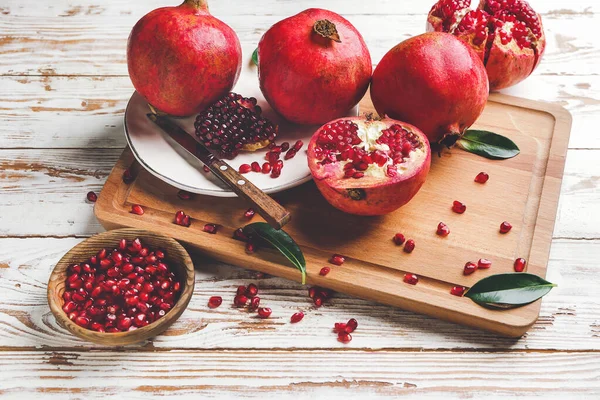 Board with tasty pomegranate on wooden table — Stock Photo, Image