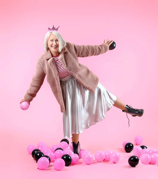 Крутая модная зрелая женщина с воздушными шарами на цветном фоне — стоковое фото