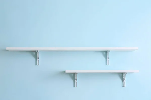 Empty shelves hanging on color wall — Stock Photo, Image