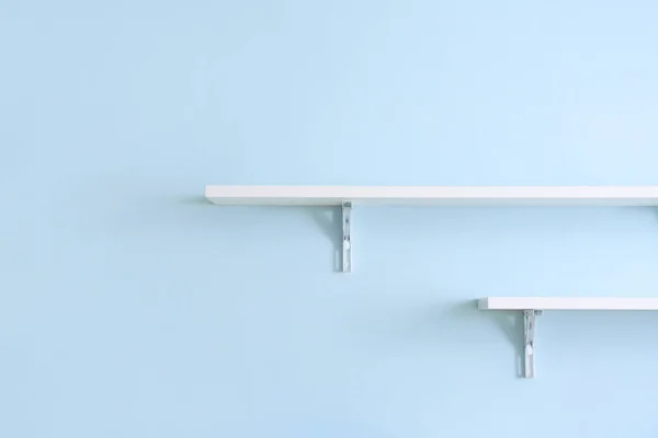 Empty shelves hanging on color wall — Stock Photo, Image