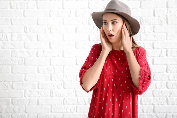 Bezorgde jonge vrouw tegen witte baksteen achtergrond — Stockfoto