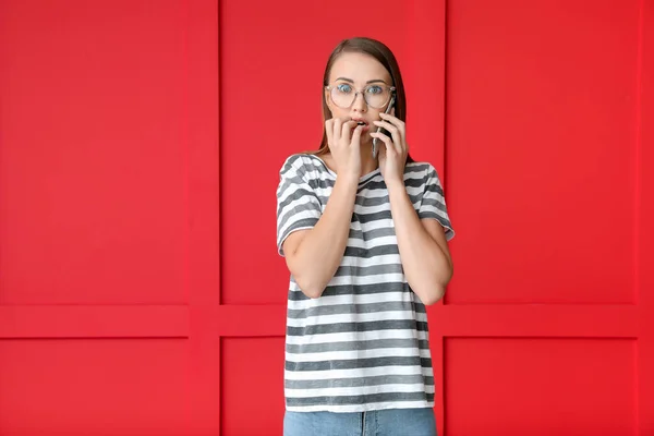 Mujer joven preocupada hablando por teléfono móvil en el fondo de color —  Fotos de Stock