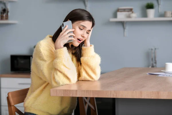 Bezorgd jonge vrouw praten via de telefoon thuis — Stockfoto