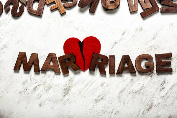 Λέξη γάμος και ραγισμένη καρδιά στο φως φόντο. Έννοια του διαζυγίου — Φωτογραφία Αρχείου