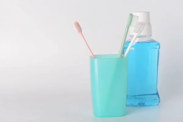 Holder with tooth brushes and mouth rinse on white background — Stock Photo, Image