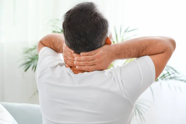 Mature man suffering from neck pain at home — Stock Photo, Image