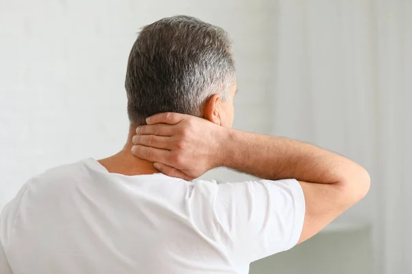 Mature man suffering from neck pain at home — Stock Photo, Image