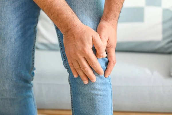 Mature man suffering from pain in knee at home, closeup — Stock Photo, Image