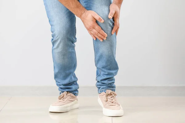 Uomo maturo che soffre di dolore al ginocchio vicino alla parete — Foto Stock