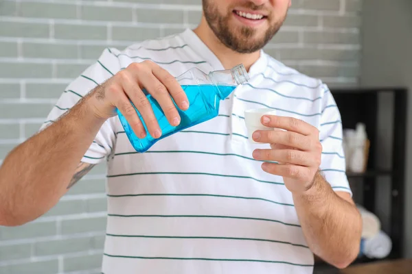 Handsome young man with mouth rinse in bathroom — Stock Photo, Image