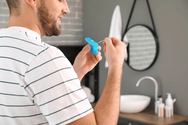 Hombre guapo que usa hilo dental en el baño — Foto de Stock