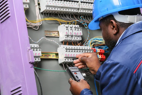 Afro-Amerikaanse elektricien voert bedrading uit in het distributiecomité — Stockfoto