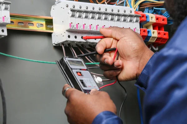 Electricista afroamericano realizando cableado en tablero de distribución, primer plano — Foto de Stock