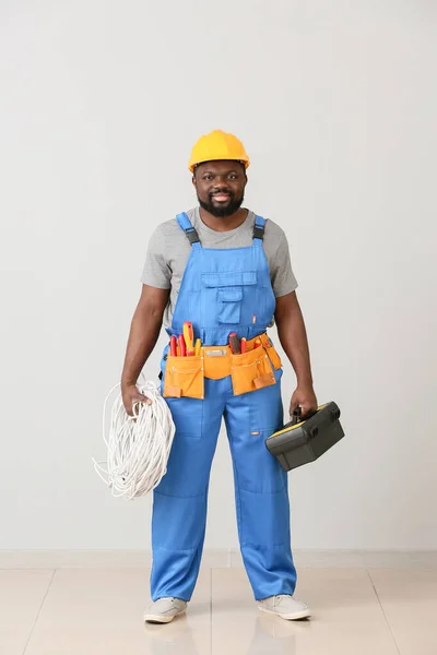 Elettricista afro-americano vicino alla parete luminosa — Foto Stock