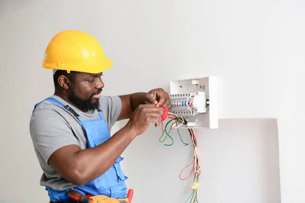 African-American electrician performing wiring in room