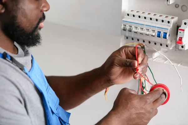 Eletricista afro-americano realizando fiação no quarto — Fotografia de Stock