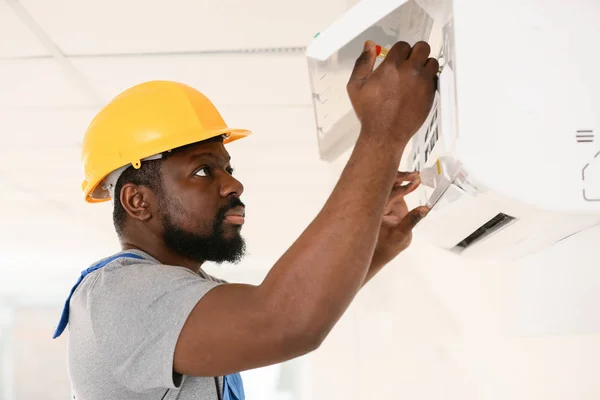 African-American electrician repairing air conditioner indoors — Stock Photo, Image