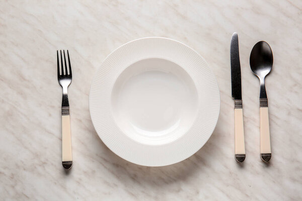 Empty plate and cutlery on light background