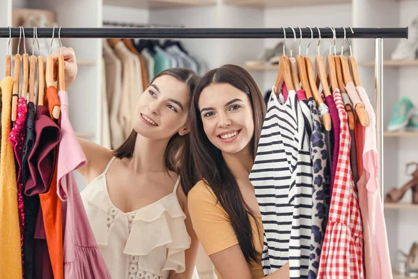Jeunes femmes choisissant des vêtements dans un magasin moderne — Photo