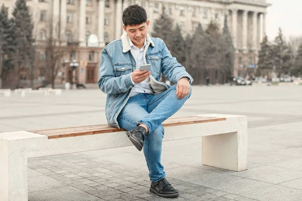 Jovem homem asiático com telefone celular ao ar livre — Fotografia de Stock