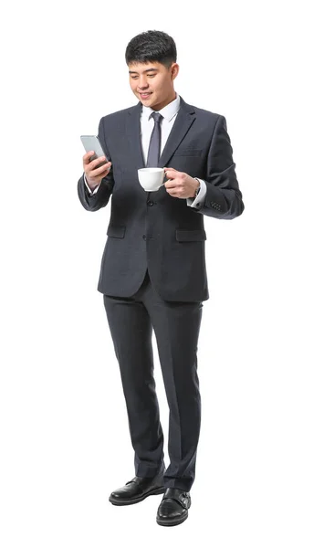 Young Asian businessman with coffee and mobile phone on white background — Stock Photo, Image