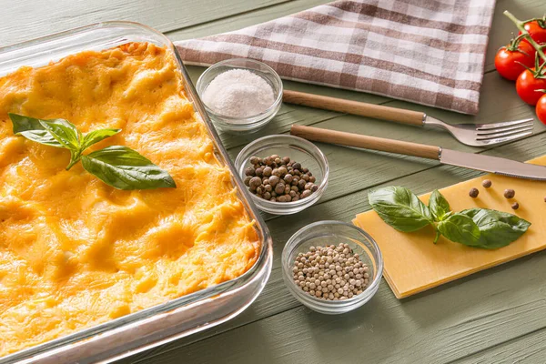 Baking dish with prepared lasagna and ingredients on wooden table — Stock Photo, Image