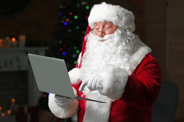 Święty Mikołaj z laptopem w pokoju udekorowane na Boże Narodzenie — Zdjęcie stockowe