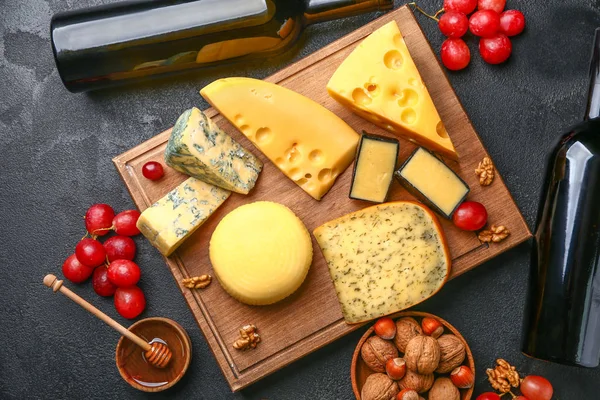 Sortimento de queijos frescos com vinho no fundo escuro — Fotografia de Stock
