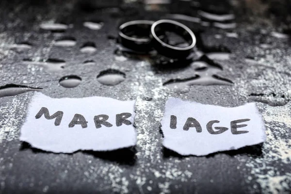 Torn paper with word MARRIAGE and rings on grunge background. Concept of divorce — Stock Photo, Image