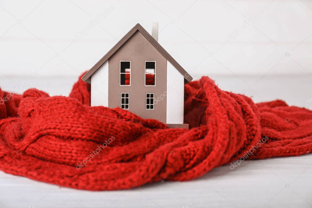 Model of house with sweater on white background. Winter concept