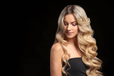 Koyu arkaplanda kıvırcık saçlı güzel bir genç kadın.