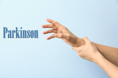 Renk arkaplanı üzerinde titreyen eller ve metin Parkinson