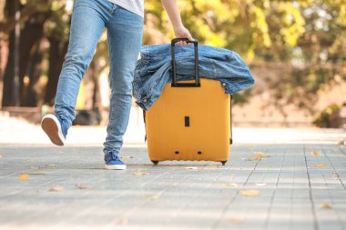 Dışarıda bagajı olan genç bir erkek turist.