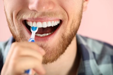 Arka planda diş fırçalayan genç adam, yakın plan.