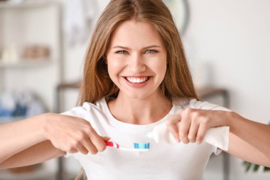 Evde diş fırçalayan genç bir kadın.