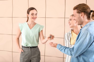 Emlakçı yeni evden genç çifte anahtar veriyor.