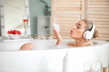 Güzel genç bayan banyoda müzik dinliyor.