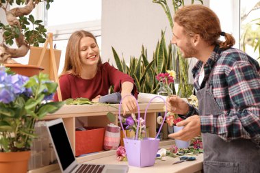 Çiçekçide düzen sağlayan genç bir kadın.