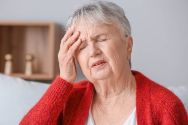 Yaşlı kadın evde baş ağrısı çekiyor.